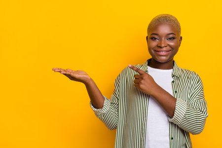 Photo of positive person direct finger hand palm demonstrate empty space proposition isolated on yellow color backgroundの写真素材