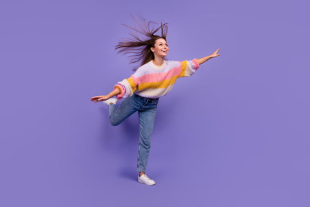 Full size portrait of overjoyed satisfied girl stand one leg arms wings flying isolated on purple color backgroundの写真素材