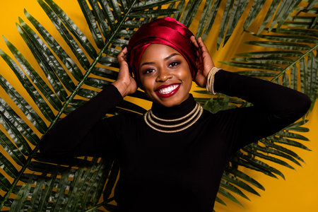 Portrait of attractive cheerful woman wearing traditional nigeria look posing isolated over bright yellow color backgroundの写真素材