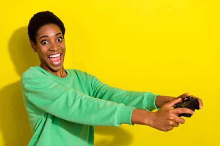 Photo of funny excited trans person wear green sweater enjoying playstation isolated yellow color backgroundの写真素材