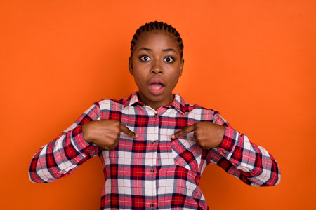 Portrait of impressed person direct fingers self open mouth cant believe isolated on orange color backgroundの写真素材