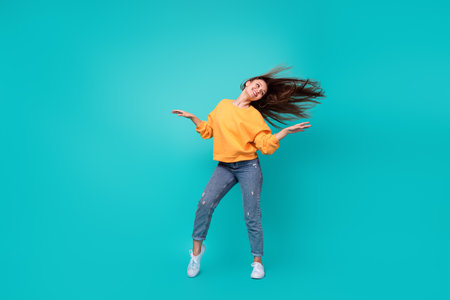 Full length photo of young attractive pretty cute woman wear orange shirt celebrate dance new holiday worker manager isolated on aquamarine color backgroundの写真素材