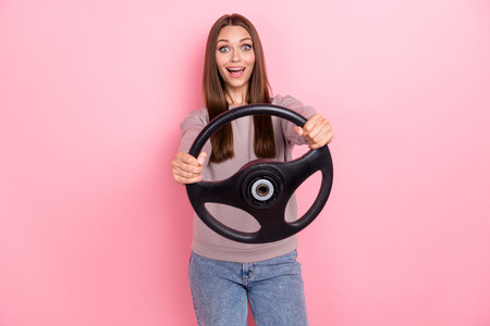 Portrait of impressed cheerful lady arms hold wheel drive fast speed isolated on pink color backgroundの写真素材
