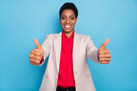 Portrait of cheerful satisfied person two arms show thumb up feedback rate isolated on blue color backgroundの写真素材