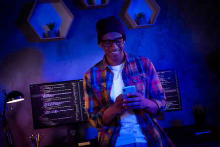 Photo of smart hacker guy hold use telephone server security operating evening workstation room indoorsの写真素材