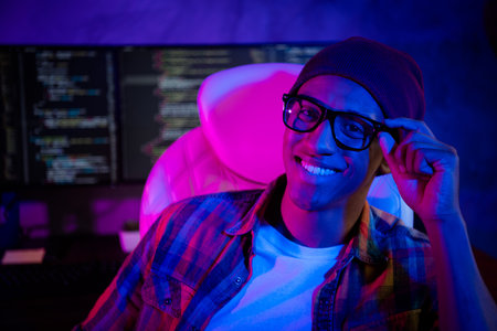 Photo of positive cheerful web designer sitting chair arm touch eyeglasses night shift workplace indoorsの写真素材