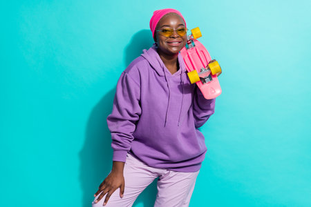 Portrait of attractive cheerful girl holding skate resting free time isolated over bright teal turquoise color backgroundの写真素材