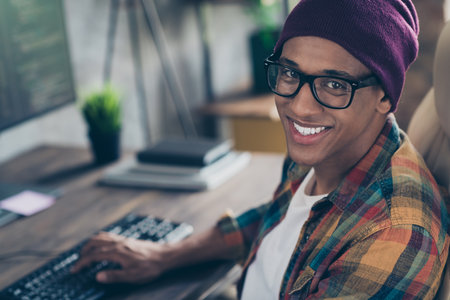 Profile portrait of positive smart web designer guy sitting chair toothy smile workstation modern office indoorsの写真素材