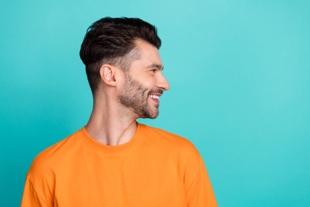 Side profile photo of young attractive handsome bearded positive smiling confident guy look empty space professional manager isolated on cyan color backgroundの写真素材
