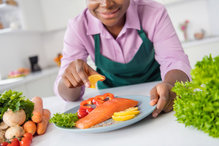 Cropped portrait of professional chef lady squeeze lemon juice salmon meat domestic restaurant indoorsの写真素材