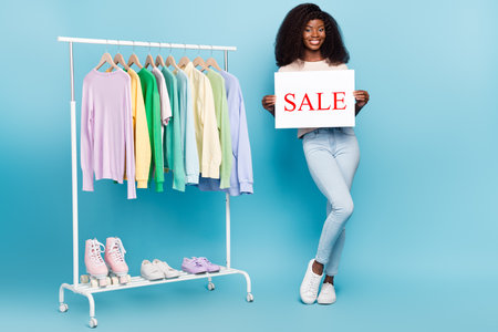 Full length portrait of positive pretty girl hands hold paper sale banner isolated on blue color backgroundの写真素材