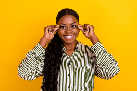 Photo of smart young brunette lady hands glasses wear striped blouse isolated on yellow color...