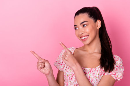 Photo of cute cheerful vietnamese girl look direct fingers empty space isolated on pink color backgroundの写真素材