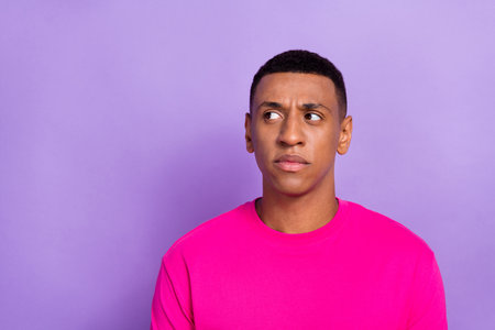 Portrait of interested suspicious curious man with fade hairstyle dressed pink t-shirt look empty pace isolated on violet color backgroundの写真素材