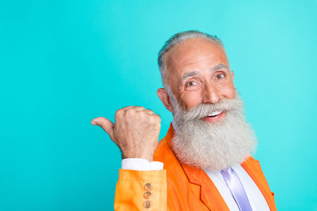 Photo of cheerful positive man toothy smile indicate thumb finger empty space isolated on emerald color backgroundの写真素材