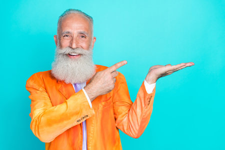 Photo of cheerful pretty retired man dressed bright orange jacket holding arm pointing empty space...