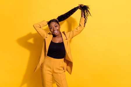 Portrait of attractive cheerful girly classy chic girl making tail having fun isolated on bright yellow color backgroundの写真素材