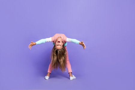 Full length photo of sportive flexible little lady dressed sweatshirt looking bak empty space isolated purple color backgroundの写真素材