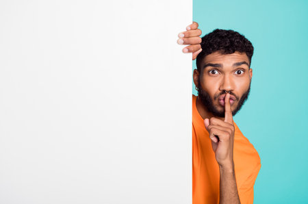Photo of young man demonstrate shh gesture empty space ad blank isolated on turquoise color...