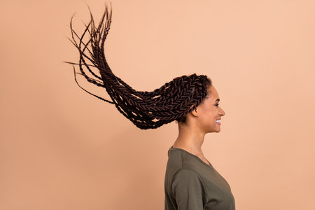 Profile portrait of cheerful pretty girl look empty space flying long hairdo isolated on beige color backgroundの写真素材