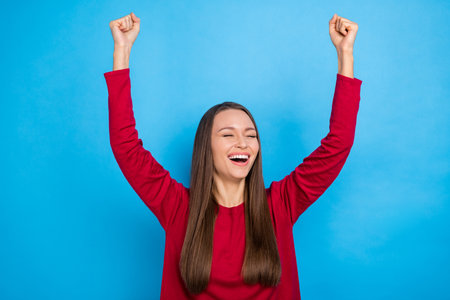 Photo of impresed long hairdo lady yell hands fists wear red shirt isolated on blue color backgroundの写真素材