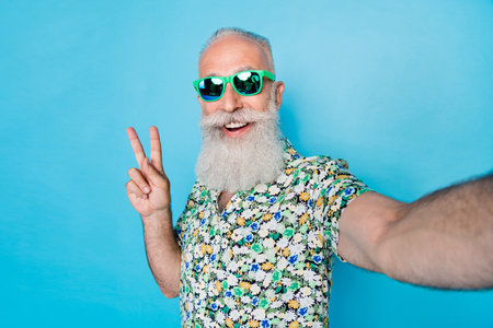 Selfie photo of old age senior grandfather excited hold camera wear  sun glasses showing v-sign...