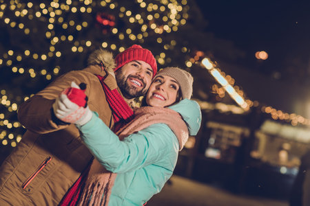 Portrait of two idyllic carefree people hold hands dance december spirit magic tree garland outsideの写真素材