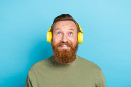 Photo of impressed guy with ginger hairstyle dressed khaki long sleeve interested look empty space isolated on teal color backgroundの写真素材