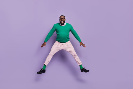 Full size photo of active cheerful overjoyed young man gentleman jumping up in excitement isolated on purple color backgroundの写真素材