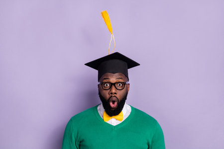 Portrait of impressed excited man student graduate university receive diploma isolated on purple color backgroundの写真素材