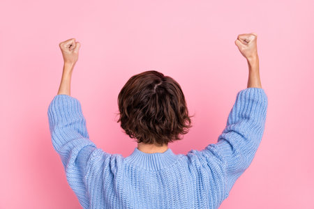 Rear spine view photo of happy lady raise hands up celebrate victory triumphant isolated on pink color backgroundの写真素材