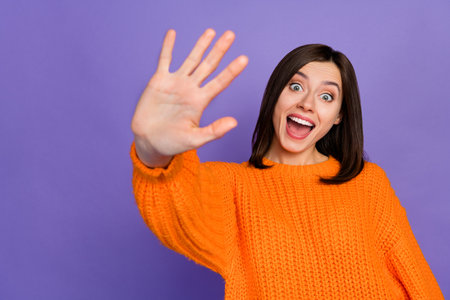 Photo of overjoyed positive girl arm palm waving hello open mouth isolated on violet color...