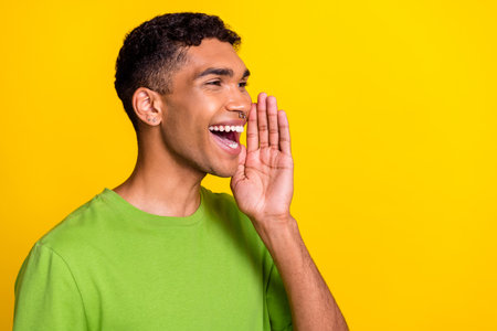 Side profile photo of young handsome positive guy hold hand whispering talking rumor information good mood look empty space isolated on yellow color backgroundの写真素材