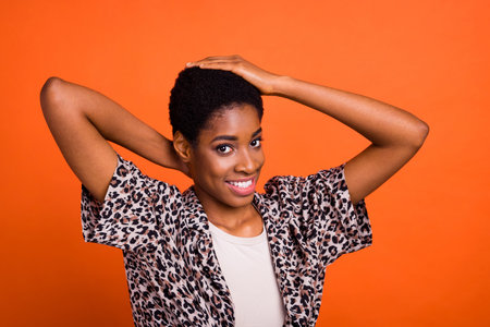 Photo of satisfied positive person hands touch new butch hairdo isolated on orange color backgroundの写真素材