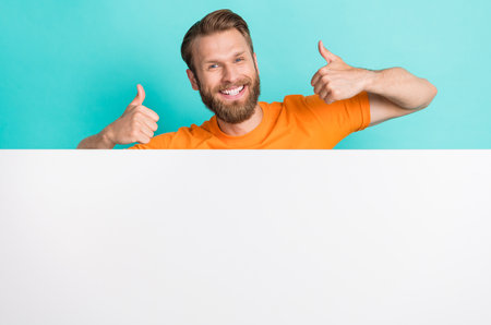 Portrait of positive handsome guy demonstrate thumbs up rate approve empty space isolated on teal color backgroundの写真素材