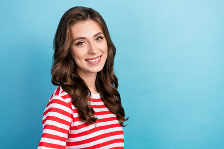 Close up photo of pretty sweet lady wear fashionable clothes demonstrates beaming smile stand empty space isolated on blue color backgroundの写真素材