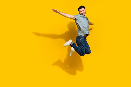Full size profile photo of cheerful satisfied person jumping arms wings flying isolated on yellow...