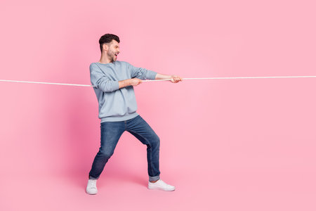 Profile side full body photo of determined guy pulling string winning isolated on pastel color...