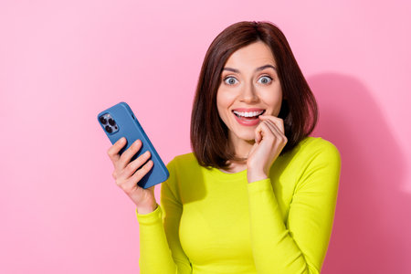 Photo of shiny cunning lady wear yellow top chatting modern gadget finger lips empty space isolated pink color backgroundの写真素材