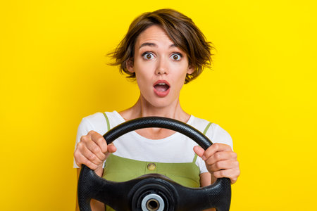 Photo portrait of gorgeous young woman driving auto afraid confused astonished wear trendy khaki outfit isolated on yellow color backgroundの写真素材