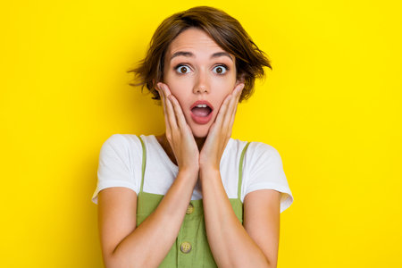 Closeup photo of funny charming woman touching cheeks nervous shocked high prices scared bankruptcy isolated on yellow color backgroundの写真素材