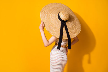 Photo of sexy adorable lady wear white outfit hand arm hat standing back empty space isolated yellow color backgroundの写真素材
