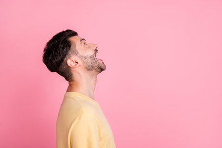 Side profile photo of nice guy with brunet hairstyle dressed yellow t-shirt look empty space screaming isolated on pink color backgroundの写真素材