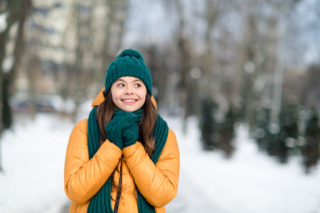 Portrait of attractive cheerful funny preteen girl wearing warm outfit going to school fantasizing december snowy weather outdoorsの写真素材