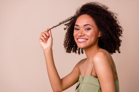 Photo of brunette millennial pretty lady hold curl wear khaki top isolated on beige color backgroundの写真素材