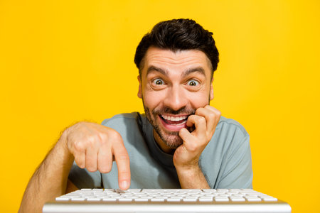 Photo of young pretty funny addicted crazy businessman gaming problem ebetting looking monitor excited good mood isolated on yellow color backgroundの写真素材