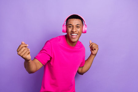 Closeup photo of young relaxed guy wear bright pink t-shirt new wireless headphones dance korean...