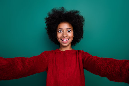 Photo portrait of cute little girl take selfie video call recording dressed stylish red knitwear look isolated on green color backgroundの写真素材