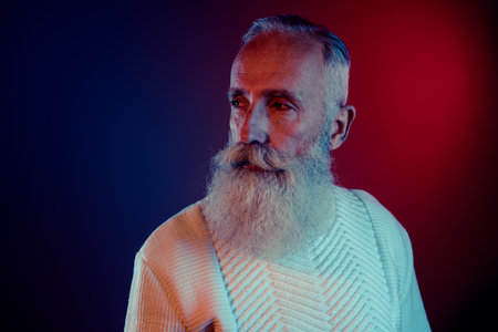 Photo of groomed masculine retired man dressed white pullover looking empty space isolated dark red...