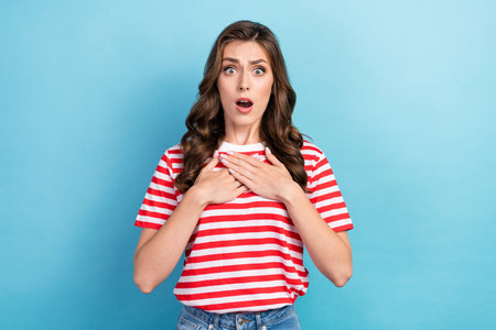 Photo of shocked impressed girl dressed red t-shirt arms chest open mouth isolated blue color backgroundの写真素材